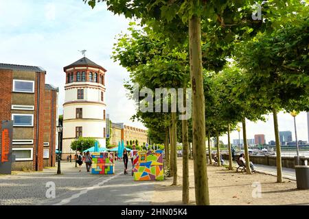 Una giornata di sole sul lungomare del Reno a Düsseldorf/Germania. La storica torre del castello è visibile sul lato sinistro. Foto Stock