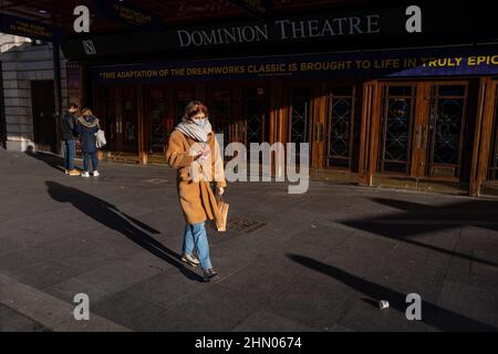 Una donna passa davanti al Dominion Theatre nel West End di Londra in una mattinata invernale allegra ma fredda. Londra, Regno Unito Foto Stock