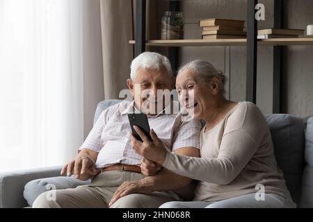 Felice eccitato coppia sposata più anziana usando lo smartphone Foto Stock