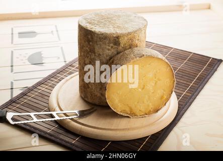 Formaggio Cheddar DOP tagliato e servito su un piatto di legno. Foto Stock