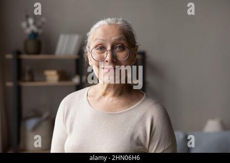 Sorridente donna anziana in occhiali eleganti testa a casa ritratto Foto Stock