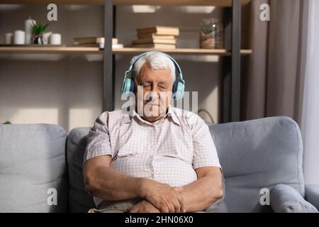 Vecchio stanco che ascolta la musica dalle grandi cuffie wireless Foto Stock