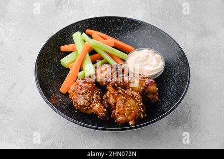 Cosce di pollo fritte con salsa teriyaki e fette di sedano e carota su un piatto Foto Stock