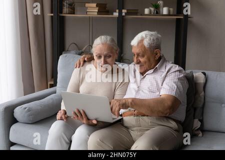 Felice sorprendo coppia matura che riposa sul divano di casa Foto Stock