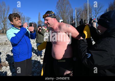 Wasserburg am Bodensee, Germania. 13th Feb 2022. Il bagnino Paul Bieber (M), di 38 anni, si imbarca dopo il suo record di nuoto sul ghiaccio nel lago di Costanza, dove fu accompagnato da bagnini in barca. Ha raggiunto il nuovo record tedesco nel Ice Mile Swim. Bieber ondeggia la distanza di 1694 metri in 36,03 minuti ad una temperatura media dell'acqua di 4,2 gradi Celsius e sette nodi di velocità del vento. Credit: Felix Kästle/dpa/Alamy Live News Foto Stock