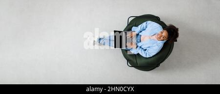 Ritratto di una donna nera sorridente che usa un computer portatile a casa Foto Stock