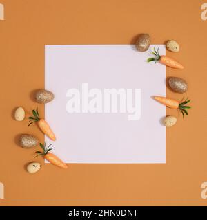 Organizzazione creativa di Pasqua minima con carote e uova d'oro intorno carta di nota. Composizione della disposizione piatta. Foto Stock