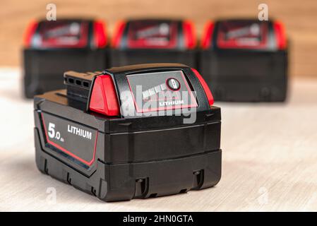 Batteria per trapano cordless. Batteria del cacciavite. Quattro batterie con indicatore di carica sono disposte su uno sfondo di legno Foto Stock