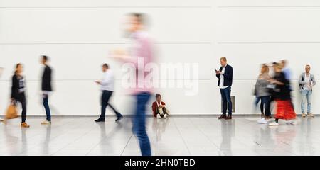 Molti anonimo sfocata persone andare in aeroporto o in una fiera commerciale Foto Stock