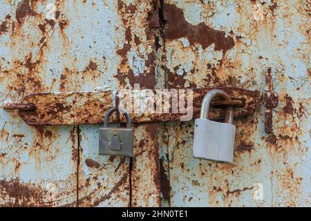 Due lucchetti su una porta in metallo arrugginito Foto Stock