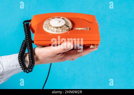 Mano con il vecchio telefono rotativo sopra blu background.Communication concetto. Foto Stock