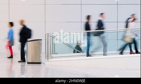 Molti anonimo la gente di affari sono a piedi attraverso un luminoso corridoio in ufficio moderno Foto Stock