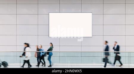 Molti visitatori della fiera camminano sotto un tabellone vuoto attraverso una sala, copyspace per il tuo testo individuale. Foto Stock