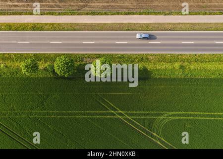 Vista aerea della strada a due corsie attraverso la campagna e campi coltivati con auto. Spazio per foto con drone e copia del testo Foto Stock