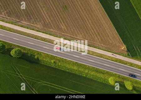 Vista aerea della strada a due corsie attraverso la campagna e campi coltivati con auto. Colpo di drone Foto Stock