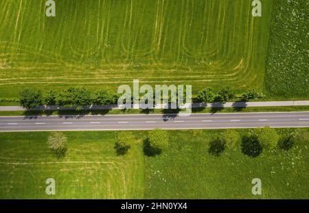 Vista aerea della strada a due corsie che attraversa la campagna e i campi coltivati. Spazio per foto con drone e copia del testo Foto Stock