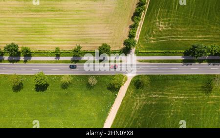 Vista aerea della strada a due corsie attraverso la campagna e campi coltivati con auto. Spazio per foto con drone e copia del testo Foto Stock