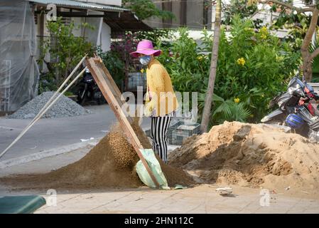 Una giovane lavoratrice femminile sfigura il terreno utilizzando un grande setaccio sulla strada a Cai Rang, vicino a Can Tho, Delta del Mekong, Vietnam del Sud, Asia sudorientale Foto Stock