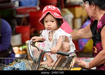 Una giovane ragazza vietnamita si siede su una bicicletta nel trafficato mercato del cibo del mattino a Cai Rang, vicino a Can Tho, Delta del Mekong, Vietnam del Sud Foto Stock
