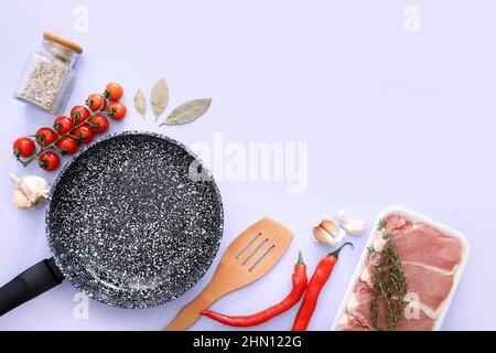 Padella in marmo nero con prodotti su sfondo lilla, vista dall'alto Foto Stock