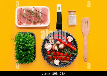 Padella in marmo nero con prodotti su sfondo giallo chiaro, vista dall'alto Foto Stock