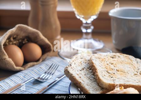 Uova sode, pane tostato e succo d'arancia. Colazione sana servita su un tavolo di legno, vista ravvicinata Foto Stock