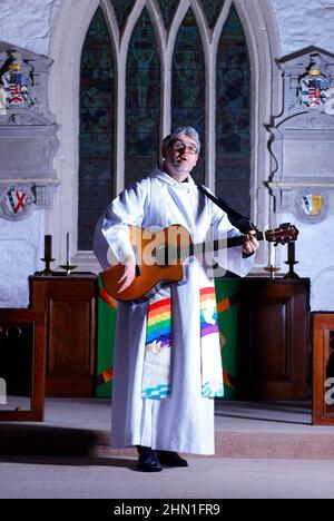 Il reverendo Bob Bailey suona la chitarra durante uno dei suoi servizi e cerimonie della chiesa alla chiesa di St Mary a Kippax, West Yorkshire UK Foto Stock