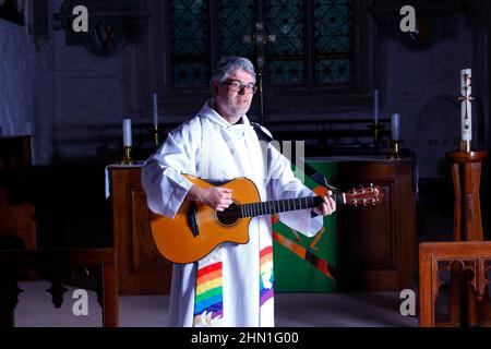 Il reverendo Bob Bailey suona la chitarra durante uno dei suoi servizi e cerimonie della chiesa alla chiesa di St Mary a Kippax, West Yorkshire UK Foto Stock