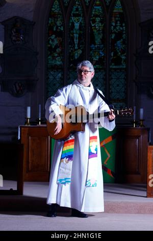 Il reverendo Bob Bailey suona la chitarra durante uno dei suoi servizi e cerimonie della chiesa alla chiesa di St Mary a Kippax, West Yorkshire UK Foto Stock