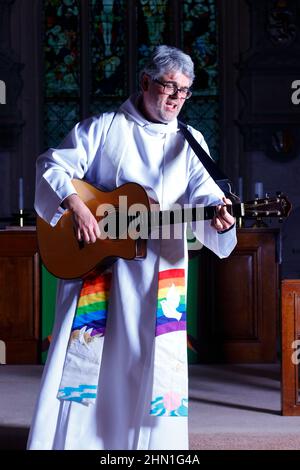 Il reverendo Bob Bailey suona la chitarra durante uno dei suoi servizi e cerimonie della chiesa alla chiesa di St Mary a Kippax, West Yorkshire UK Foto Stock