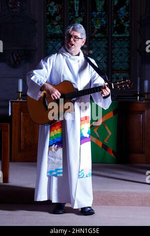 Il reverendo Bob Bailey suona la chitarra durante uno dei suoi servizi e cerimonie della chiesa alla chiesa di St Mary a Kippax, West Yorkshire UK Foto Stock