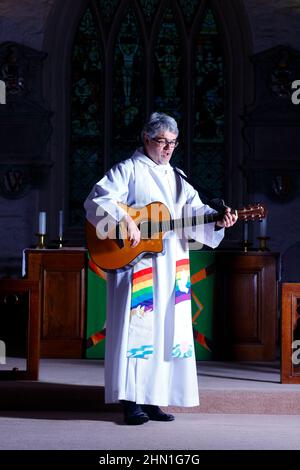 Il reverendo Bob Bailey suona la chitarra durante uno dei suoi servizi e cerimonie della chiesa alla chiesa di St Mary a Kippax, West Yorkshire UK Foto Stock