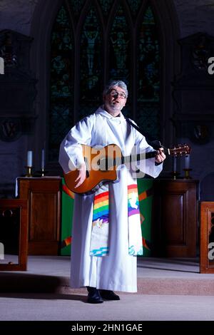 Il reverendo Bob Bailey suona la chitarra durante uno dei suoi servizi e cerimonie della chiesa alla chiesa di St Mary a Kippax, West Yorkshire UK Foto Stock