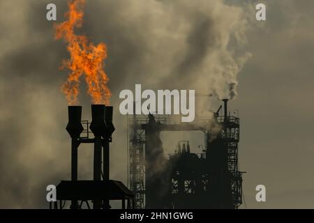 Camini industriali pesanti che producono fumo e fuoco. Illustrazione dell'inquinamento atmosferico e danni agli organi respiratori. Riscaldamento globale e industria del carbone Foto Stock