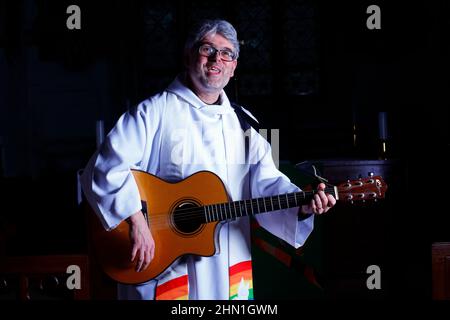 Il reverendo Bob Bailey suona la chitarra durante uno dei suoi servizi e cerimonie della chiesa alla chiesa di St Mary a Kippax, West Yorkshire UK Foto Stock