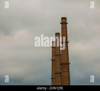 Inquinamento dell'aria causato dal fumo proveniente da tre camini di fabbrica. Il concetto di inquinamento atmosferico, problemi ambientali, emissioni atmosferiche Foto Stock