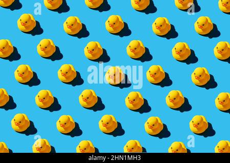 Modello di giocattoli anatra in gomma gialla su sfondo blu senza cuciture. Brillante design di banner concettuali. Foto Stock