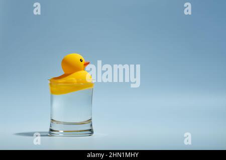 Anatra di gomma gialla giocattolo che galleggia in un bicchiere d'acqua. Foto Stock