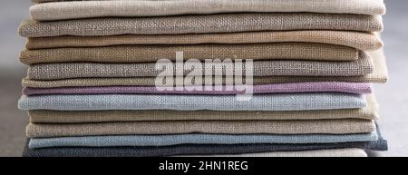Un mucchio di quattro tessuti di lino naturale piegati di colore opaco, eco-compatibile, su sfondo rustico, banner Foto Stock