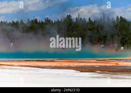 I turisti si sono avvolti di vapore che si innalza dalla sorgente prismatica Grand, dal bacino del geyser Midway, da Yellowstone NP, Wyoming Foto Stock