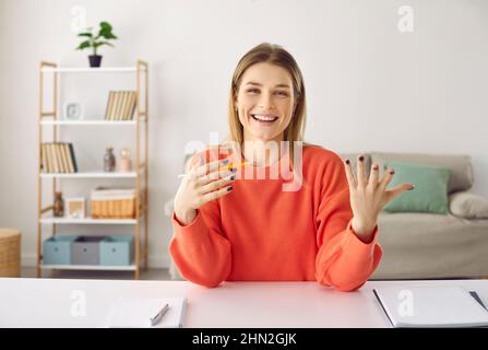 Donna positiva che parla e conduce consulenza online o formazione mentre si siede in ufficio a casa. Foto Stock