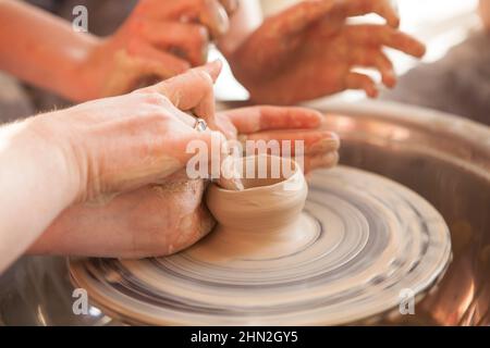 Vasaio irriconoscibile che mostra agli studenti come gettare pentola sulla ruota vasai Foto Stock
