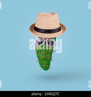 Cactus verde in occhiali da sole alla moda con cappello su sfondo blu. Minimal Summer Concept. Foto Stock