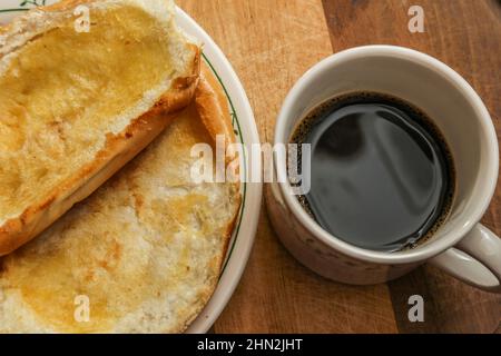 Goiânia, Goias, Brasile – 13 febbraio 2022: Due ciambelle sul piatto e una tazza di caffè su una superficie di legno. Foto Stock