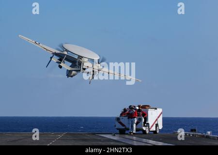 MAR DELLE FILIPPINE (Feb 13, 2022) un e-2D Hawkeye, assegnato ai 'Wallbangers' del vettore Airborne Early Warning Squadron (VAW) 117, lancia dal ponte di volo del vettore aereo di classe Nimitz USS Abraham Lincoln (CVN 72) a sostegno dell'esercizio 22 Jungle Warfare (JWX 22) attraverso Okinawa, Giappone, 13 febbraio 2022. JWX 22 è un esercizio di formazione sul campo su larga scala incentrato sull'utilizzo delle capacità integrate di partner congiunti e alleati per rafforzare la consapevolezza, le manovre e gli incendi di tutti i domini in un ambiente marittimo distribuito. (STATI UNITI Foto Navy di See Foto Stock