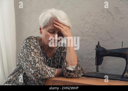 anziana depressa donna che soffre di demenza seduta e toccare la fronte con una mano. Foto di alta qualità Foto Stock