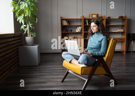 Giovane donna che indossa cuffie che studiano online su laptop, agente del centro di contatto remoto che lavora da casa Foto Stock