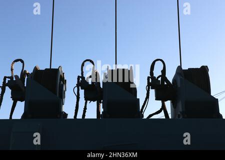 Silhouette di tre argani per imbarcazioni, Monterey Bay Harbour, California. Potenti sistemi a puleggia utilizzati nell'industria nautica. Foto Stock