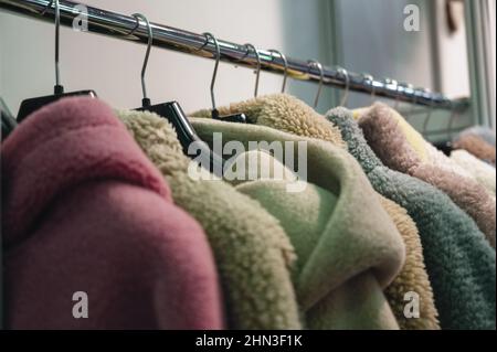 Eleganti cappotti e giacche in pelliccia sintetica appendono sul rack Foto Stock