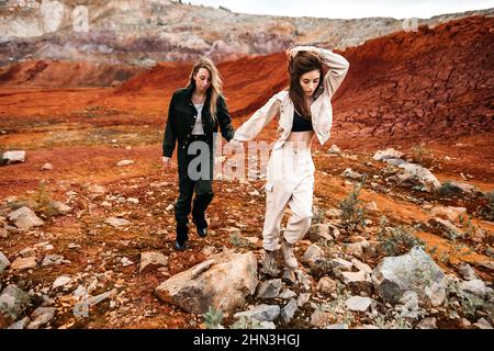 Ragazze in un posto post-apocalittico, una cava con terra rossa e pietre in abiti da lavoro. Foto di alta qualità Foto Stock